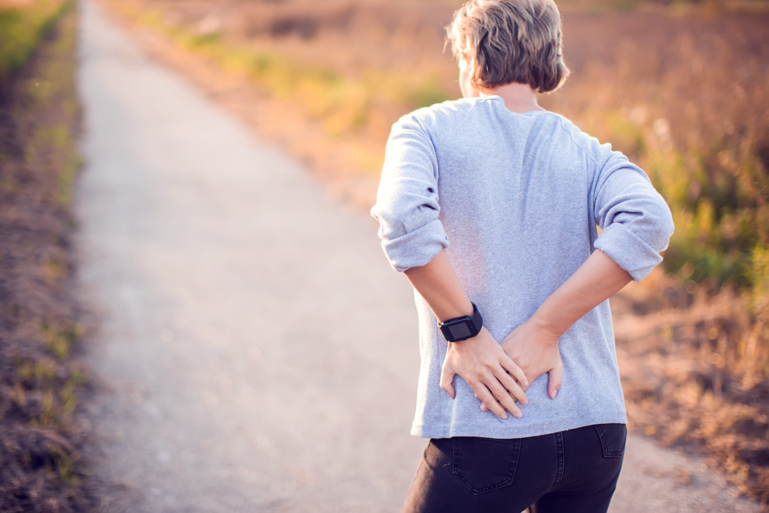 elder woman walking on a trail and is having lower back pain