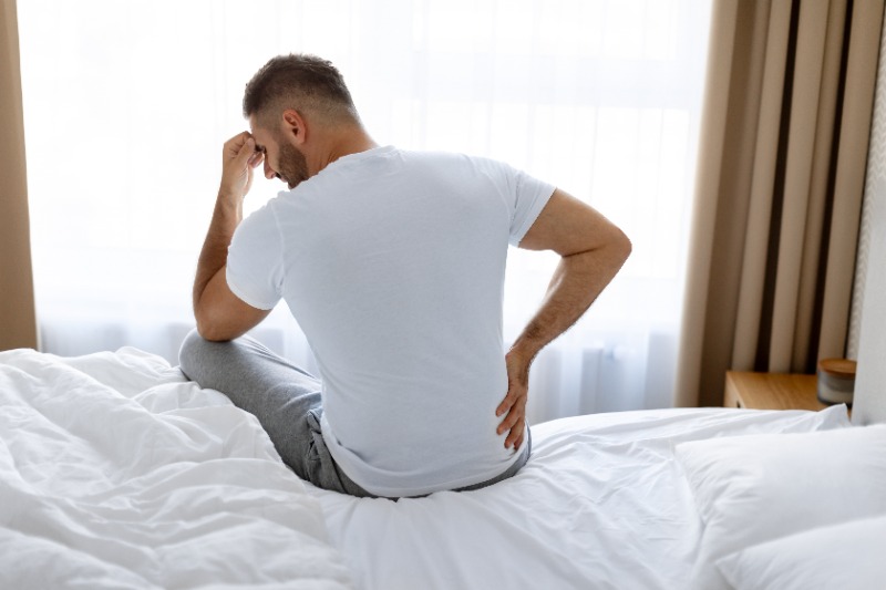 man-sitting-on-bed-in-pain-after-sciatica-at-night