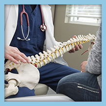 Male doctor demonstrating a spine bone model to a female patient
